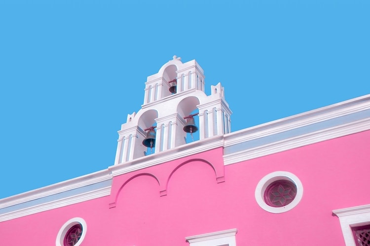 Pink building with blue sky behind showing how beautiful ordinary places are for summer vacation